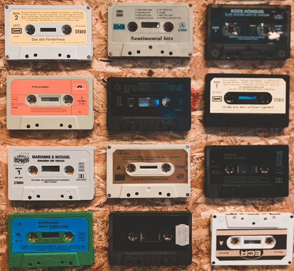 Close-up of retro cassette tapes with colorful album designs on a wooden table.