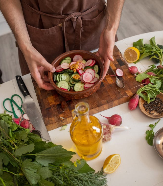 Hands carefully chopping fresh vegetables on a wooden cutting board, showcasing the art of home cooking.